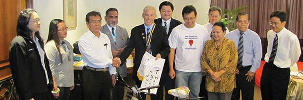 OVER TO YOU: Juergen (fifth right) symbolically hands over a bicycle to Masan. Zainie (fourth left) is one of those looking on.
